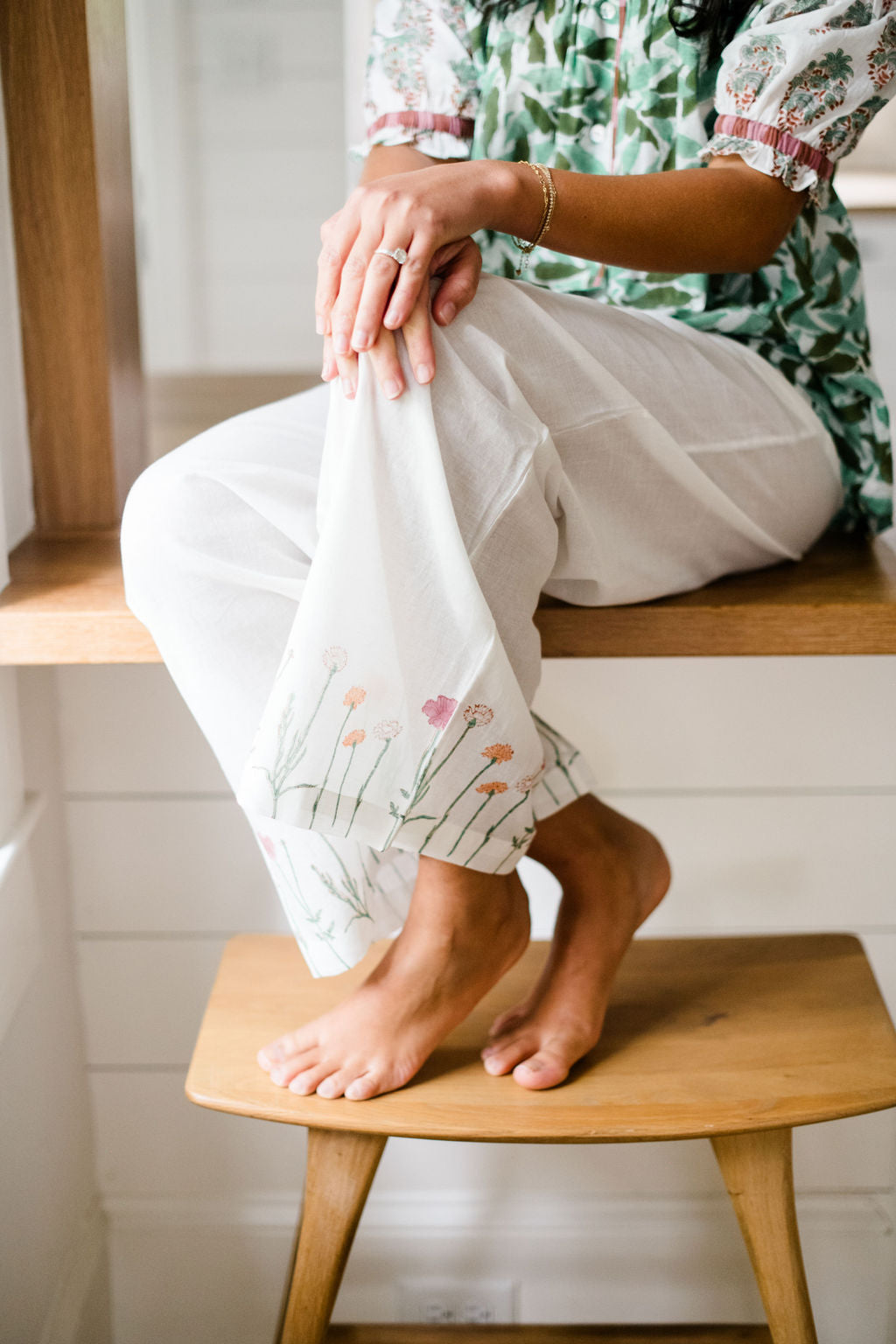 Close-up of woman sitting on a kitchen counter in the Winnie Top and Logan Pant by Sundara – relaxed cotton loungewear with hand-block printed details and effortless style.