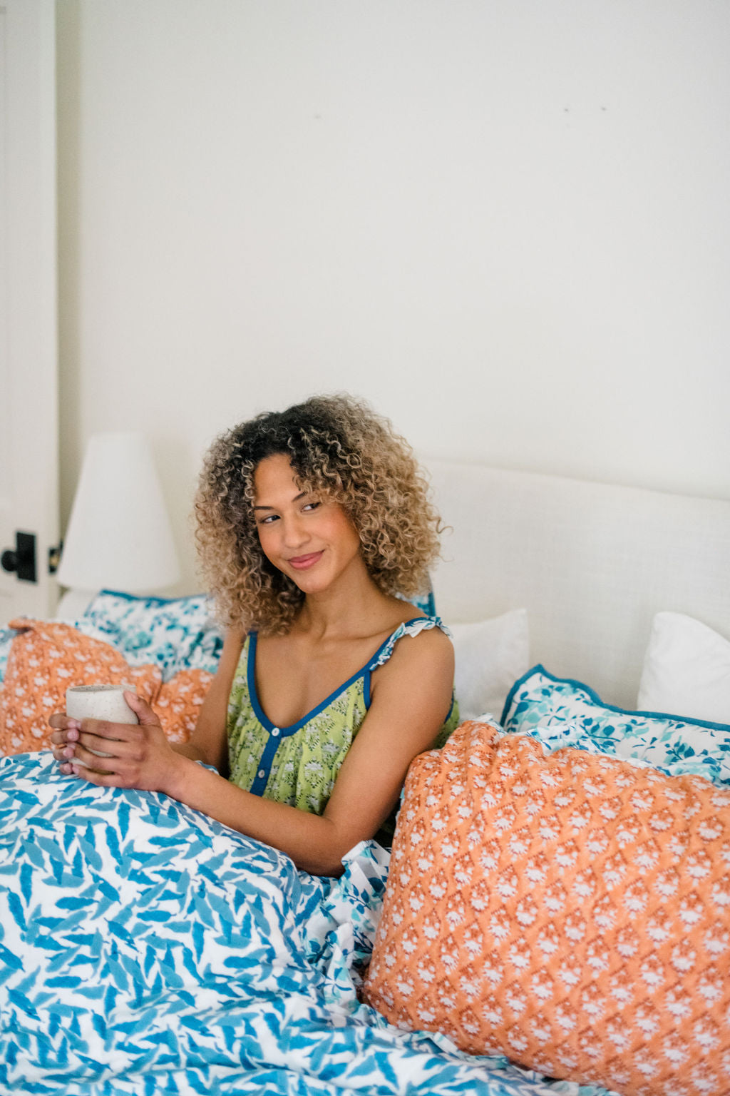 Woman in bed wearing the Madi Top by Sundara – a comfortable, hand-block printed cotton top, perfect for relaxing at home in cozy, stylish comfort.
