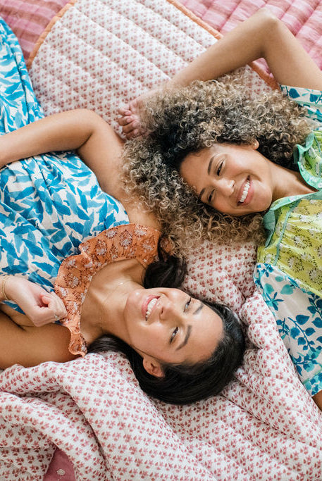 Women lounging on a bed in Sundara’s Joce Nightgown and Dorothy Top – relaxed, block-printed cotton sleepwear designed for comfort and beauty.