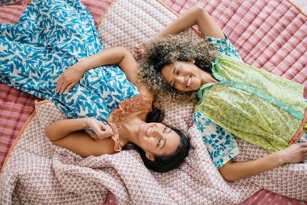 Women lounging on a bed in Sundara’s Joce Nightgown and Dorothy Top – relaxed, block-printed cotton sleepwear designed for comfort and beauty.