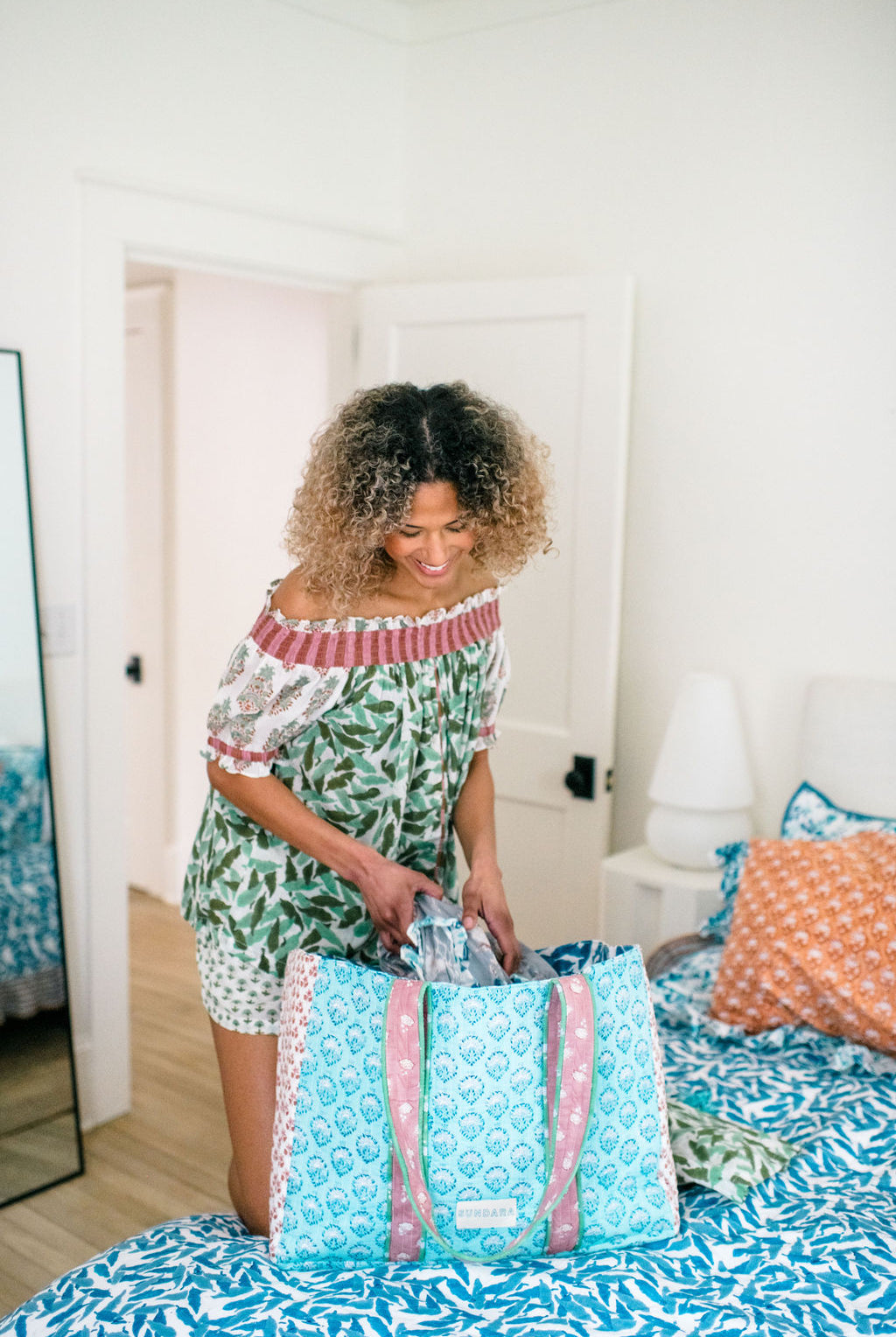 Woman in Sundara pajamas packing the quilted tote bag – effortlessly combining comfort and style as she prepares for a day of relaxation or adventure.