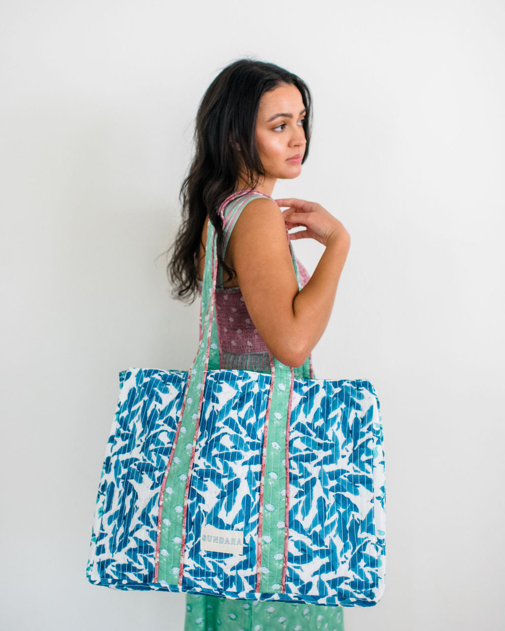 Woman carrying the Sundara quilted tote bag on her shoulder – a spacious and stylish carryall perfect for everyday use, showcasing its luxurious design