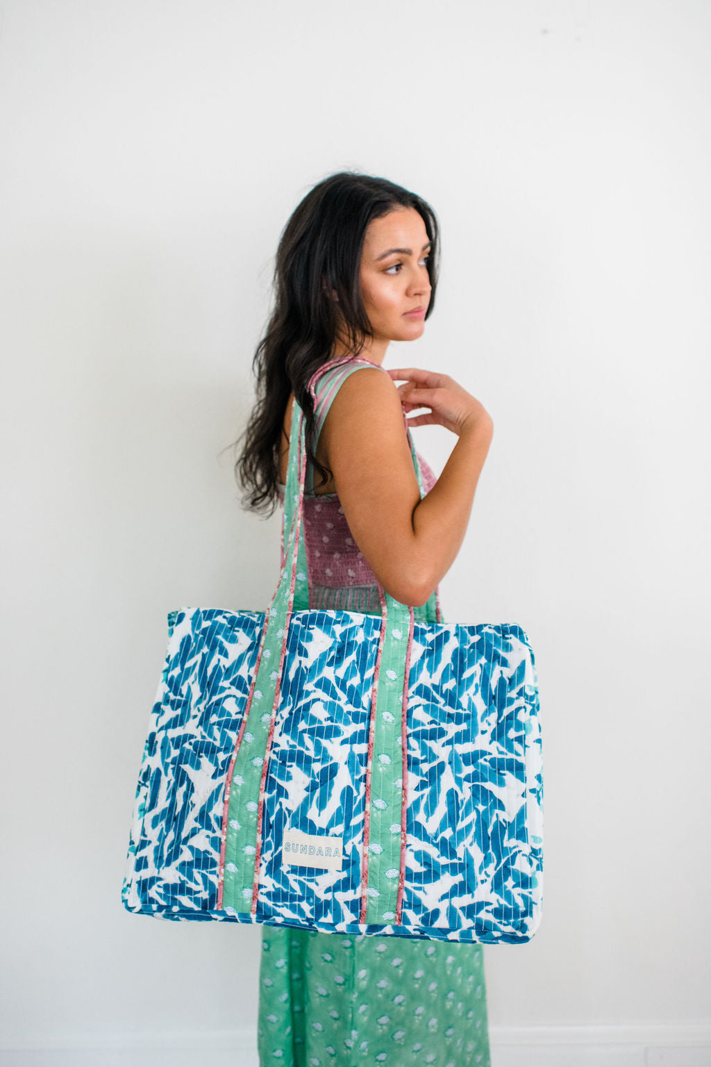 Woman carrying the Sundara quilted tote bag on her shoulder – a spacious and stylish carryall perfect for everyday use, showcasing its luxurious design