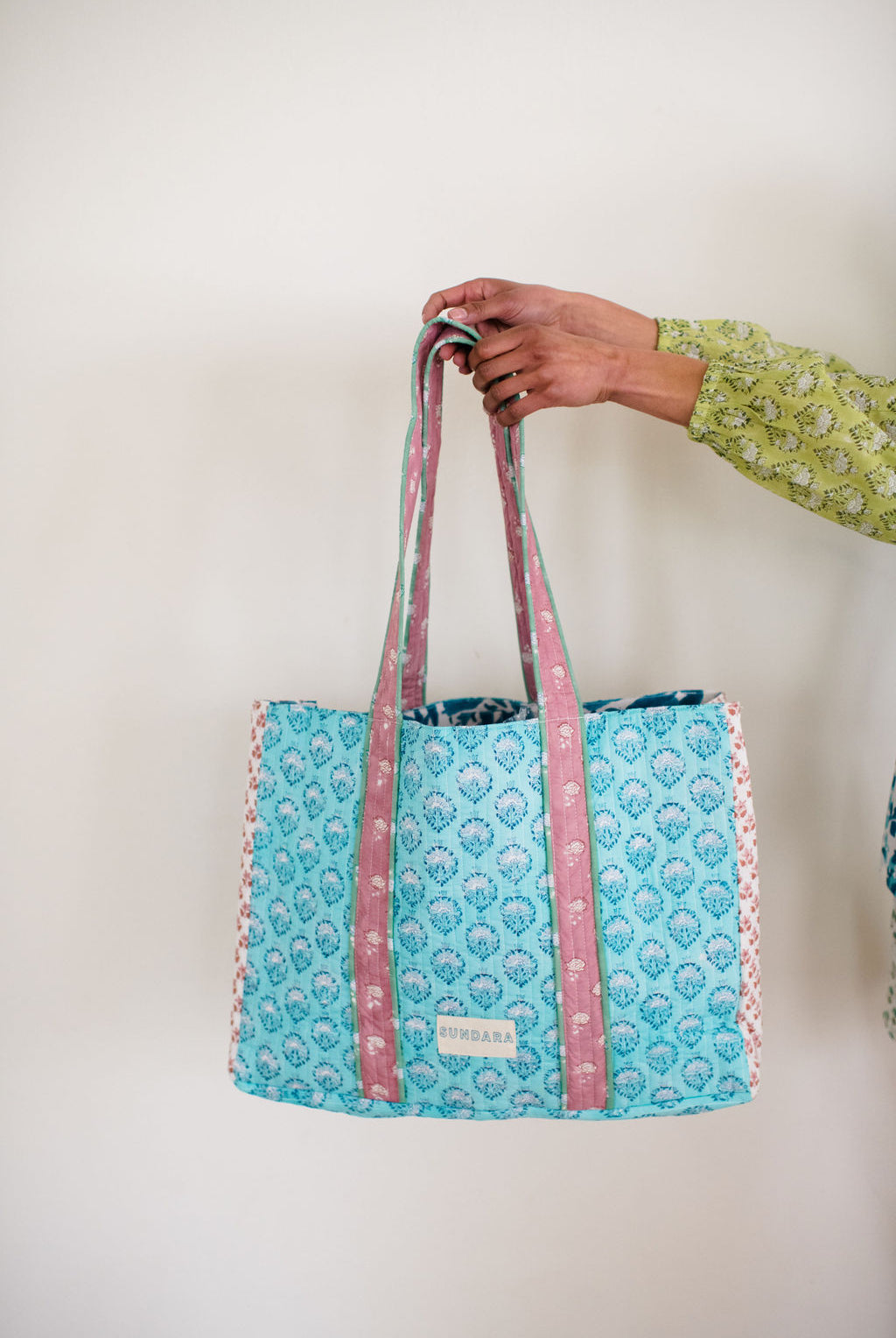 Sundara quilted tote bag on her shoulder – a spacious and stylish carryall perfect for everyday use, showcasing its luxurious design