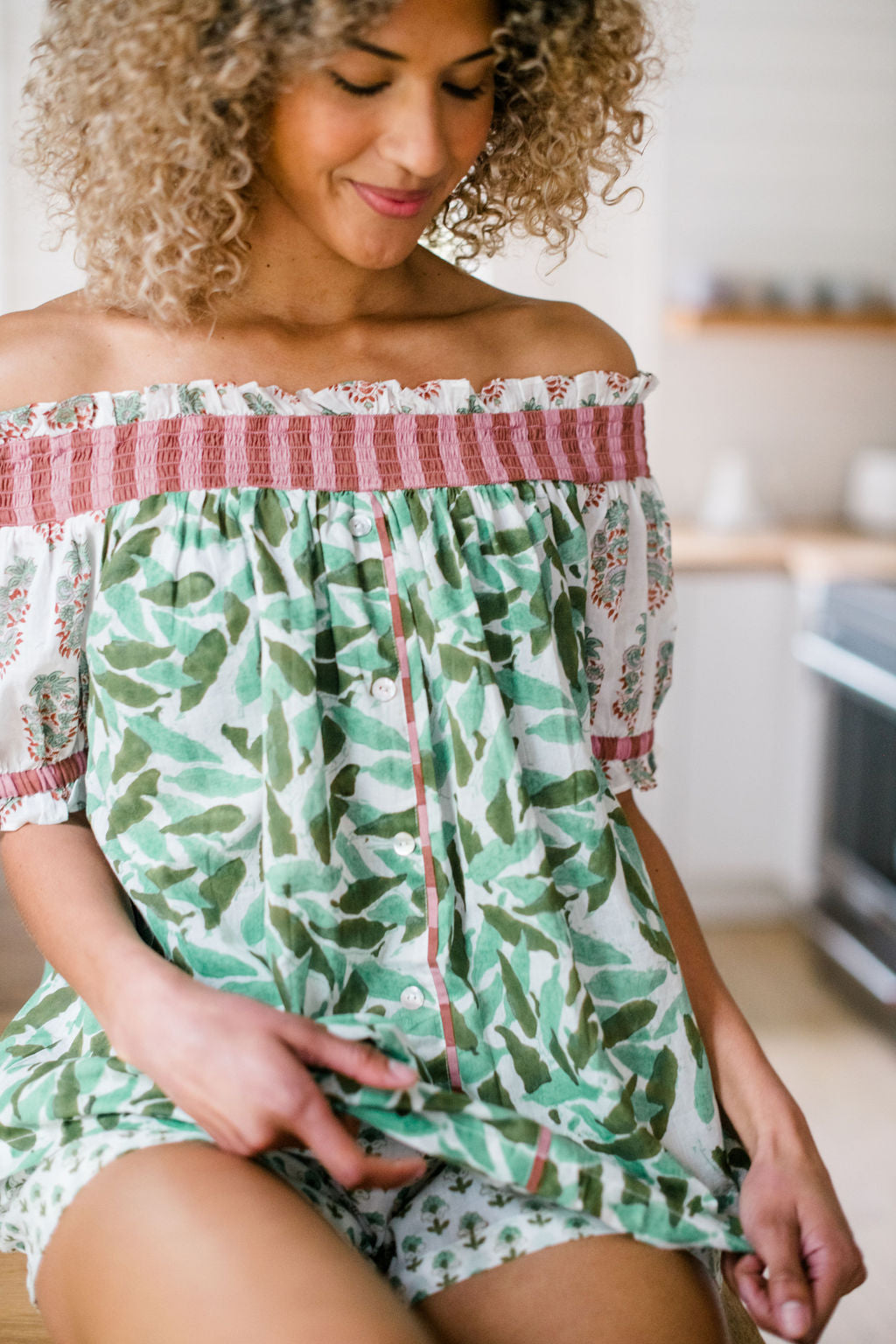 A woman wearing The Winnie Top by Sundara – a relaxed cotton pajama top with off-the-shoulder styling, featuring delicate hand-block prints for a laid-back, stylish look.