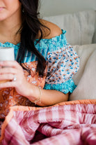 Close-up of the Winnie Top by Sundara – a soft cotton pajama top with delicate block prints, paired with a luxurious quilt for added comfort and style